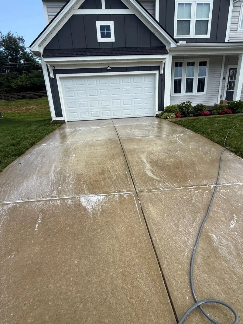 Driveway cleaning in front of a blue home
